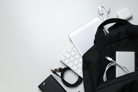 Backpack with power bank, cords and tablet on white background, space for textの写真素材