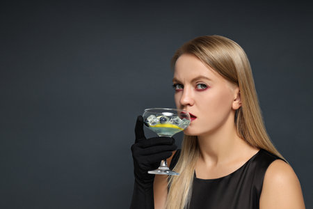 A girl at a party in the style of Halloween with a cocktail in her handsの写真素材