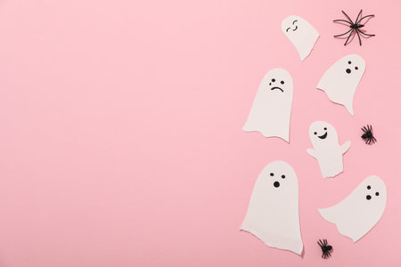 Decorative spiders and paper ghosts on pink background, space for textの写真素材