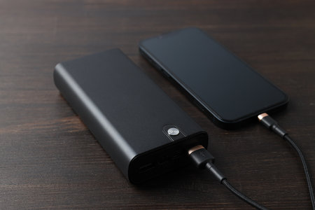 Powerbank and smartphone on wooden background, close up