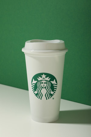 Ukraine, Kyiv, 08/24/2023: A cup of Starbucks coffee with the logo, on a green background.のeditorial素材