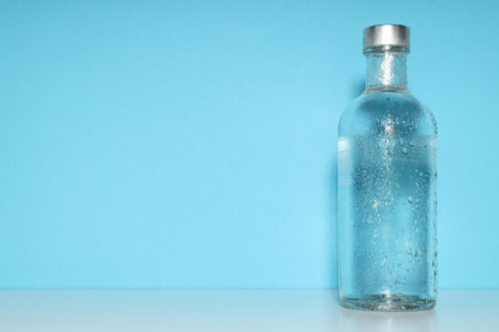 Glass bottle on blue background, space for textの写真素材