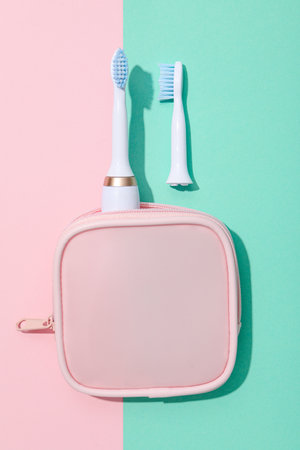Electric toothbrushes and case on pink and green background, top viewの写真素材