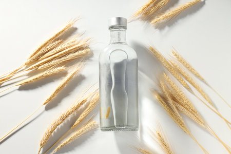 Glass bottle and spikelets on white background, top viewの写真素材