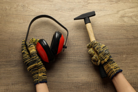 Hammer and headphones in hands on wooden background, top viewの写真素材