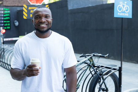 A stylish, young African-American man with a coffee in his hand in a bicycle parking lotの写真素材