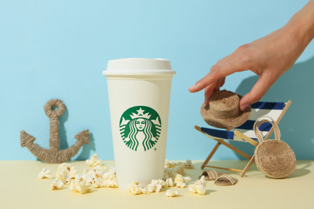 Ukraine, Kyiv, 24/08/2023: A cup of Starbucks coffee with a logo, on the background of a sea composition.のeditorial素材