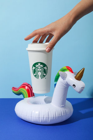 Ukraine, Kyiv, 08/24/2023: Starbucks coffee cup with logo, in an inflatable unicorn.のeditorial素材