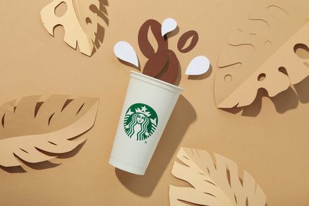 Ukraine, Kyiv, 08/24/2023: Starbucks coffee cup with logo, with whole coffee beans.のeditorial素材