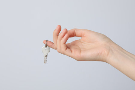 Female hand with a key on the finger on a light backgroundの写真素材