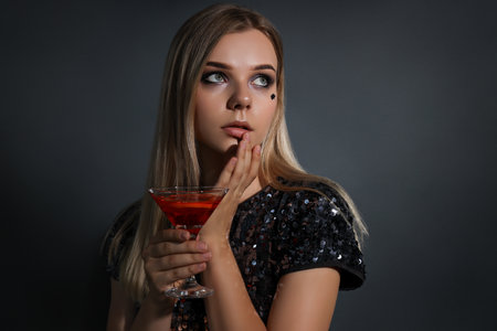 A girl at a party in the style of Halloween with a cocktail in her handsの写真素材
