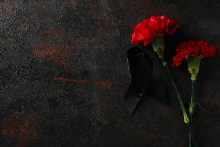 Flowers and black ribbon on dark background, space for textの写真素材