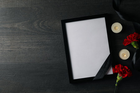Candles, photo frame with black ribbon and flowers on wooden background, space for textの写真素材