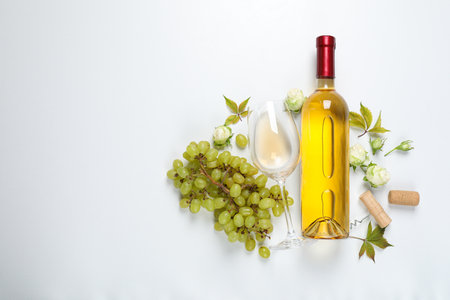 Glass bottle, glass, grapes and roses on white background, space for textの写真素材