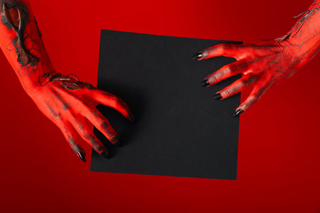 Spooky, red hands of the monster hold a black sheetの写真素材