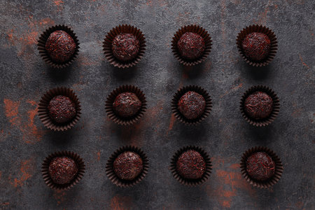 Brigadeiro in paper forms on dark gray background, top view