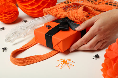 Gift box in string bag, spiders and hand on white backgroundの写真素材