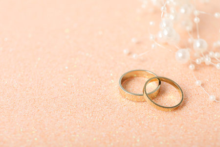 Golden wedding rings on beige background, space for textの写真素材