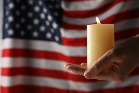 Mourning candle in hands on the background of the American flagの写真素材