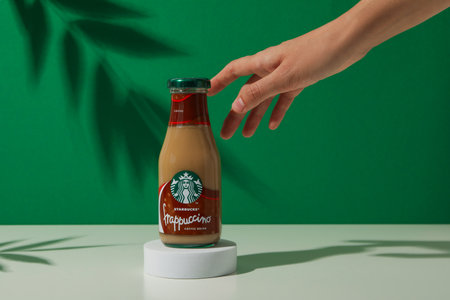 Ukraine, Kyiv, 08/24/2023: Starbucks frappuccino bottle with logo, on a green background.