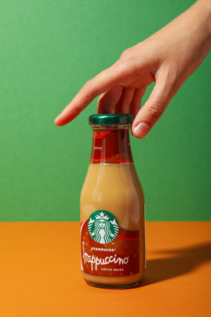 Ukraine, Kyiv, 08/24/2023: Starbucks frappuccino bottle with logo, on a green background.