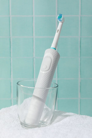 Electric toothbrush in glass on towel on blue backgroundの写真素材