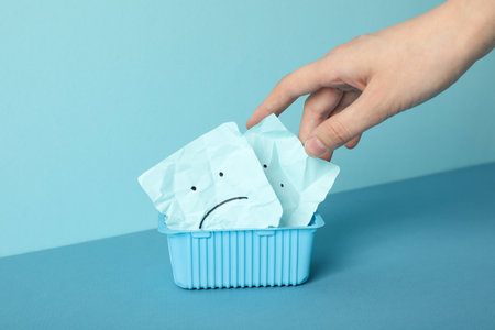 Plastic box, paper with notes and hand on blue backgroundの写真素材