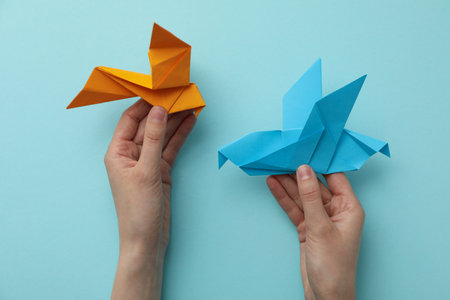 Decorative paper birds in hands on blue background, top viewの写真素材