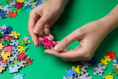 Colored puzzles in hands on green background, close upの写真素材
