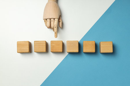 Wooden cubes and hand on white and blue background, top viewの写真素材