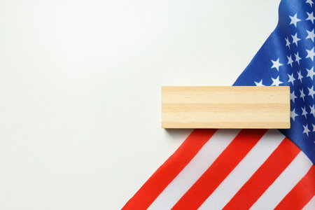 Wooden block and America flag on white background, space for textの写真素材