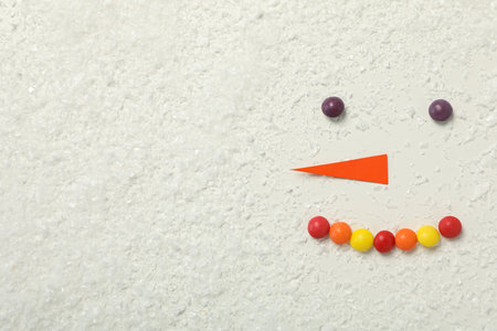 The face of a snowman with paper carrots and candiesの写真素材