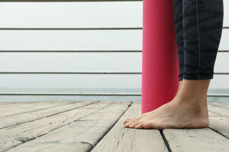 Female legs and yoga mat on wooden floor outdoors, space for textの写真素材