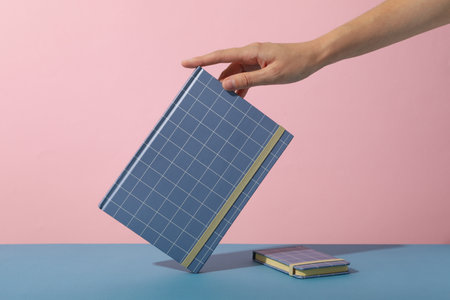 Notepads and female hand on pink background