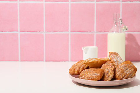 Madeleine cakes and milk bottle on pink background, space for textの写真素材