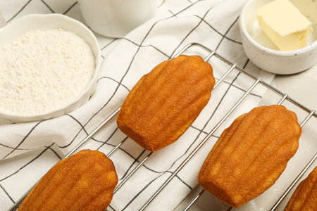 Madeleine cakes, butter and flour in bowls on light background