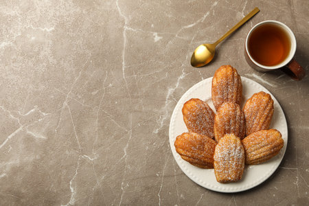 Madeleine cakes, spoon and cup of tea on gray background, space for textの写真素材