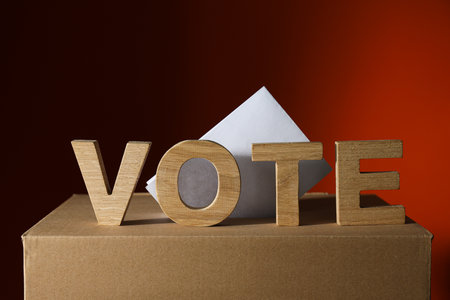 Voting box with form and wooden letters on dark backgroundの写真素材