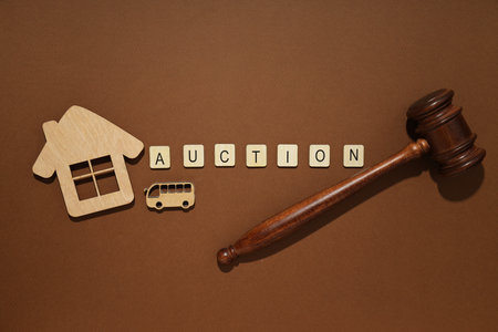 Word Auction, wooden figures and hammer on brown background, top view