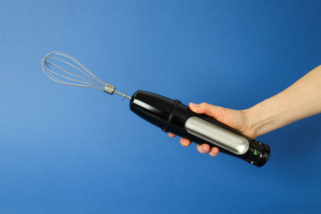 Black blender with whiskey in hand on blue backgroundの写真素材