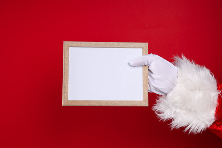 Wooden photo frame in Santa's hand on red backgroundの写真素材