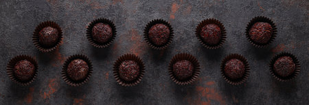 Brigadeiro in paper forms on dark gray background, top view