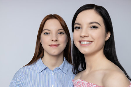 Two sisters pose on a light backgroundの写真素材