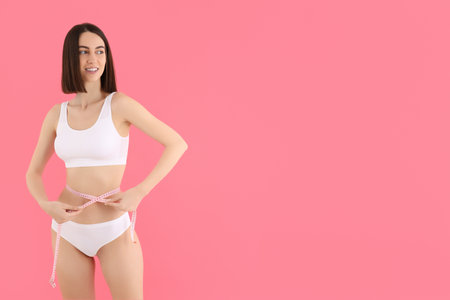 A slim girl in underwear measures her waist.の写真素材
