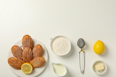 Madeleine cakes, cream, flour, butter and lemon on white background, space for textの写真素材