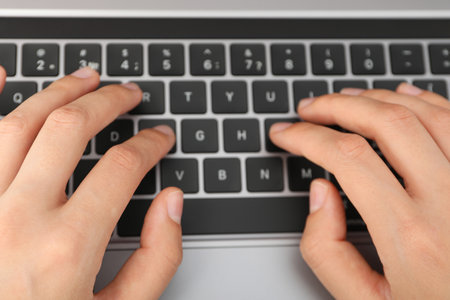 Hands on black laptop keyboard close up view