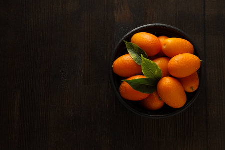 Kumquat and bowl on wooden background, space for textの写真素材