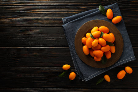 Kumquat on plate and towel on wooden background, space for textの写真素材
