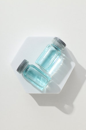 Glass medical bottles with vaccine on white background, top view