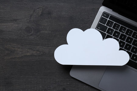 White paper cloud with laptop on black table background